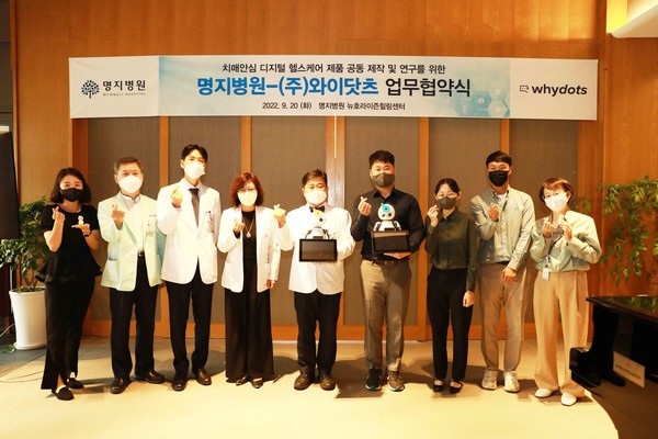 Myongji Hospital President Kim Jin-goo (center) and Why Dots CEO Yoon Young-seop (to Kim's right) pose for a photo after signing the cooperation agreement to co-develop an AI robot for dementia patients.