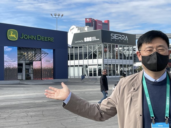 The writer stands in front of the exhibition halls of Sierra Space and John Deere standing side by side at CES 2022.