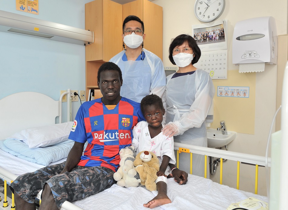 Gloria, a Sudanese girl who swallowed a metal piece, has been cured after receiving surgeries from Professor Park Seong-yong (standing at right) at Severance Hospital. (Severance)