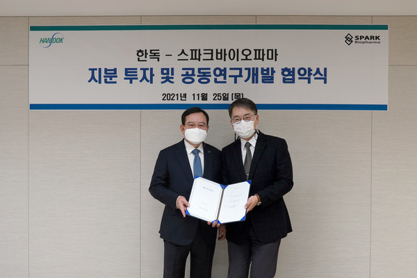 Handok CEO Kim Young-jin (left) and Spark Biopharma CEO Park Seung-bum hold up the cooperation agreement at Handok headquarters in Gangnam-gu, Seoul.