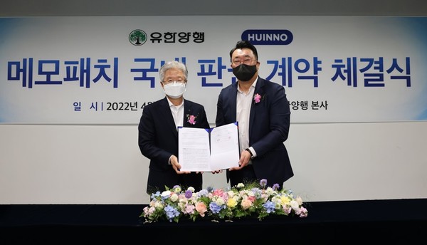 Yuhan Corp. CEO Cho Wook-je (left) and Huinno CEO Gil Yeong-joon hold up the sales agreement at Yuhan’s headquarters in Dongjak-gu, Seoul, Tuesday.
