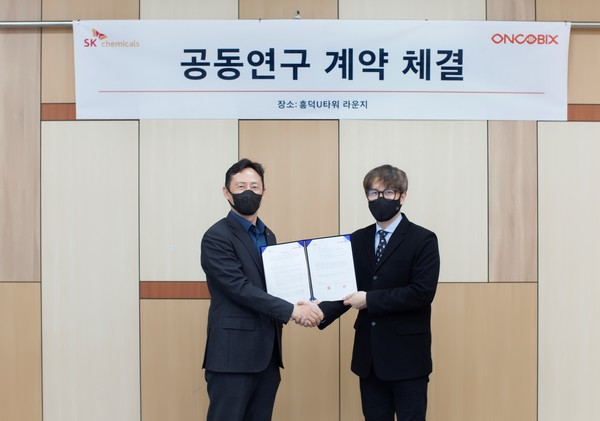 SK Chemicals R&D Center Director Kim Jeong-hoon (left) and Oncobix CEO Kim Seong-eung shake hands after signing the cooperation agreement at the Oncobix headquarters in Yongin, Gyeonggi Province, on Wednesday.