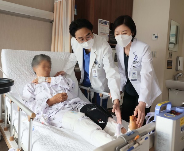 Professors Park (center) and Choi care for an artificial joint surgery patient at the hospital.
