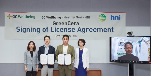 HNI CEO Shin Hyung-sik (second from left) and GC Wellbeing CEO Kim Sang-hyun hold their agreement as Healthy Navi CEO Toshitada Inoue looks on the TV screen during the technology transfer contract signing ceremony  Thursday.