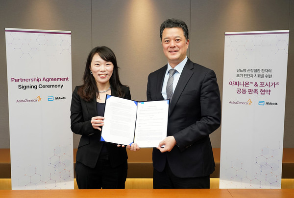Abbott Rapid Diagnostics Korea Director Heo Jeong-seon (left) and AstraZeneca Korea Director Shim Il pose after signing a partnership agreement in Seoul, Tuesday.