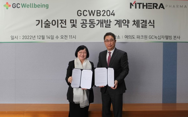GC Wellbeing CEO Kim Sang-hyun (right) and MThera Pharma Son Mi-won hold up their technology transfer agreement at GC Wellbeing headquarters in Yeouido, Seoul, Wednesday.