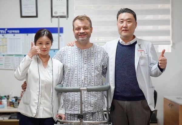 From right, Lee Chun Tek Hospital Director Yoon Sung-hwan, Russian patient, Igor Mishanov, and a surgical nurse pose after the successful hip replacement surgery at the Lee Chun Tek Orthopedic Speciality Hospital in Suwon.
