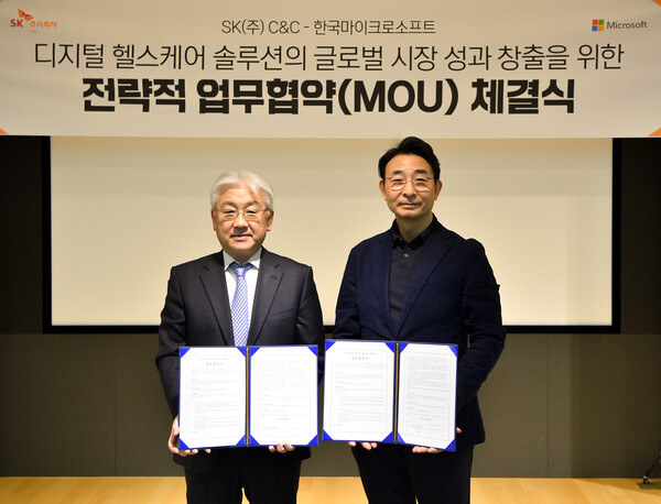 SK C&C Healthcare Division Head Yoon Dong-june (left) and Microsoft Korea Public Sector Senior Director Lee Sang-hyun hold up their cooperative agreement at SK-u tower in Bundang, Gyeonggi Province, Thursday.