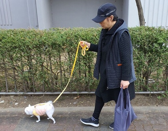 Baek Geum-seon, a stage-four lung cancer patient, walks her dog around her apartment. She could lead a normal daily life after taking Tagrisso, she said. 