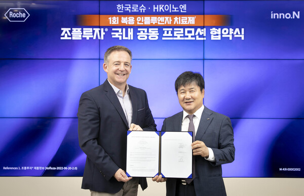 Roche Korea General Manager Nic Horridge (left) and HK inno.N CEO Kwak Dal-won hold up the exclusive distribution and co-commercialization agreement at Roche Korea headquarters in Gangnam-gu, Seoul, Thursday.