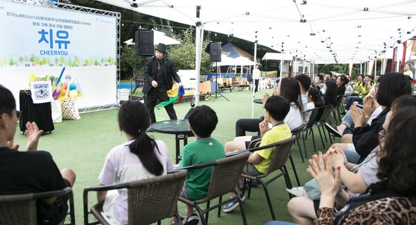 Patients with rare and intractable diseases and their caregivers watch a magic show during the CHEERYOU program at the Pine Valley Glamping Site in Pocheon, Gyeonggi Province, last Friday.