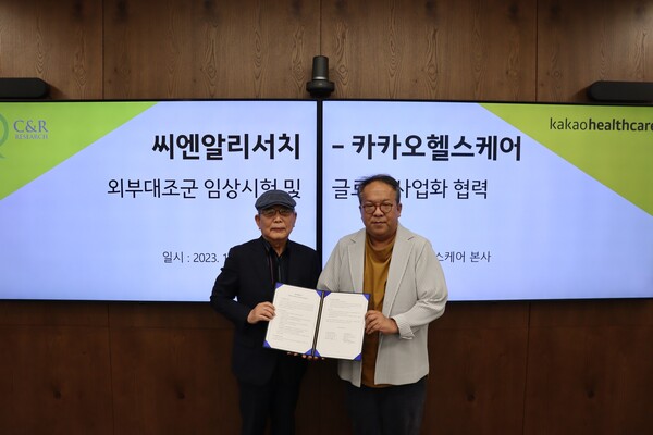 Kakao Healthcare CEO Hwang Hee (right) and C&R Research CEO Yoon Moon-tae hold up the cooperation agreement at Kakao Healthcare headquarters in Seongnam, Gyeonggi Province, Thursday.