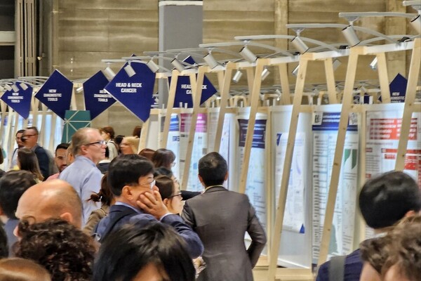 TiumBio CEO Kim Hoon-taek (second from left) looks at poster presentations at the ESMO 2023. (KBR photo)