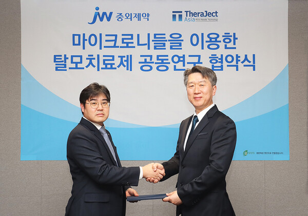 Jin Se-ho (left), Head of Raw Material Research Center at JW Pharmaceutical, and Kim Kyoung-dong, CEO of Theraject Asia,  pose for a photo after signing the agreement in Seoul. (Courtesy of JW Pharmaceutical)
