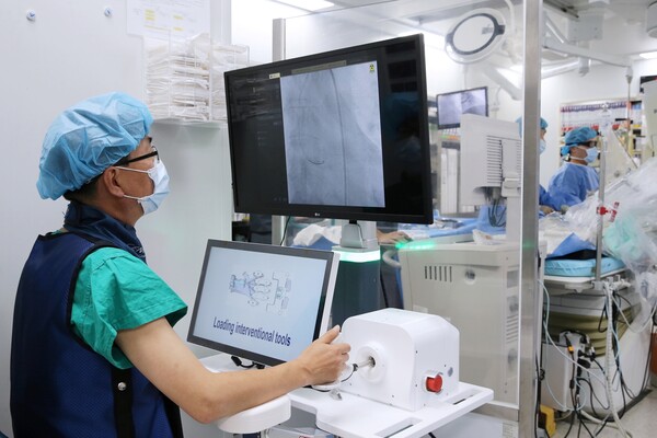Professors Lee Seung-hwan and Kim Tae-oh of the Department of Cardiology at Asan Medical Center in Seoul perform percutaneous coronary intervention using the first homegrown robot for that purpose. (Courtesy of Asan Medical Center)