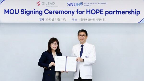 Gilead Sciences Korea Director of Clinical Operation Stella Ha (left) and SNUH Clinical Trials Center Director Kim Dong-wan hold up the MOU to cooperate on developing new oncology drugs at SNUH in Jongno-gu, downtown Seoul, last Thursday.