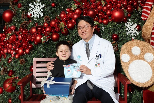Professor Choi Jong-woo at AMC (right) and Alinur, the Kyrgyzstan boy who received facial reconstruction surgery at the hospital, pose for a commemorative photo after successfully completing the surgery at AMC in Songpa-gu, Seoul, on Tuesday. (credit: AMC)