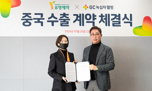 GC Wellbeing CEO Kim Sang-hyun (right) and YooYoung Pharmaceutical CEO Yoo Jup-yong hold up the business agreement at GC headquarters in Yongin, Gyeonggi Province, last Friday.