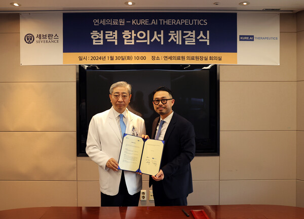 Yonsei University Health System President and CEO Yoon Dong-sup (left) and KURE.AI Therapeutics Co-founder Hwang Tae-hyun hold up the cooperation agreement at Yonsei University Health System Seodaemun-gu, Seoul, on Tuesday.