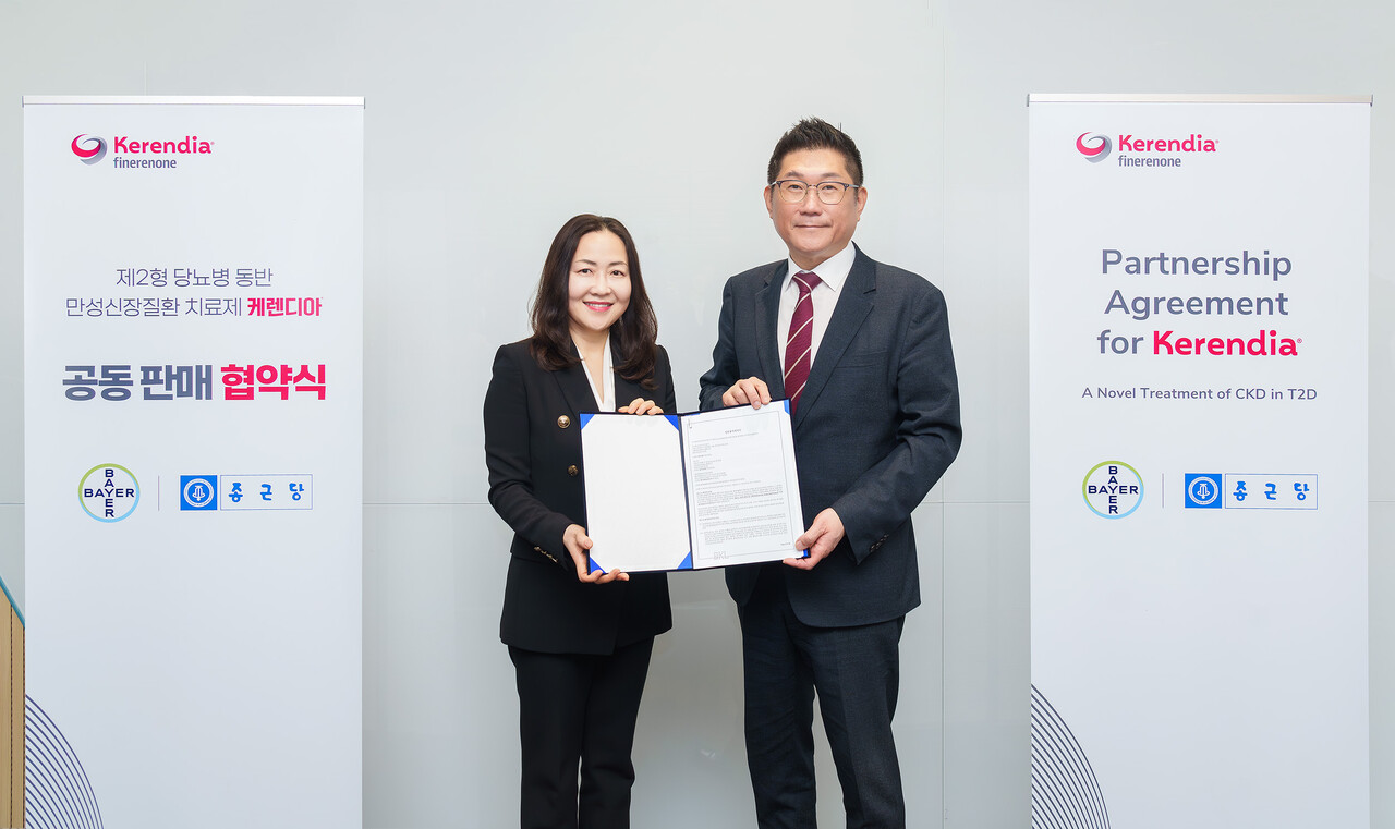 Bayer Korea CEO Lee Jin-a (left) and Chong Kun Dang CEO Kim Young-joo hold up the co-promotion agreement at Bayer Korea headquarters in Yeongdeungpo-gu, Seoul, Wednesday.